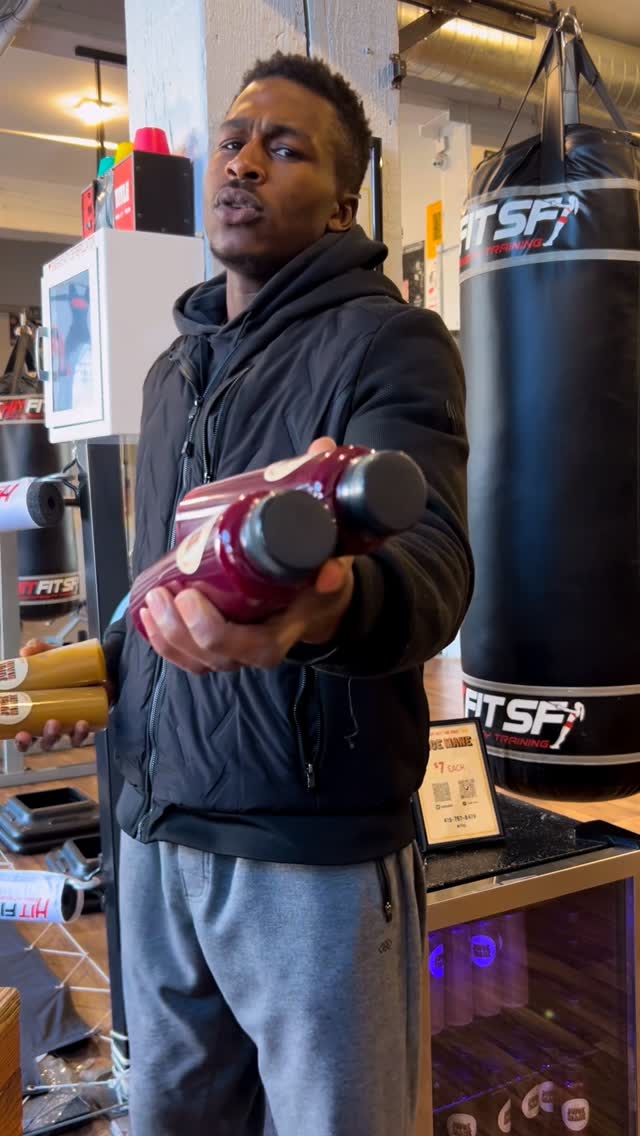 A member on the gym floor at Hit Fit SF, in front of the branded heavy bags