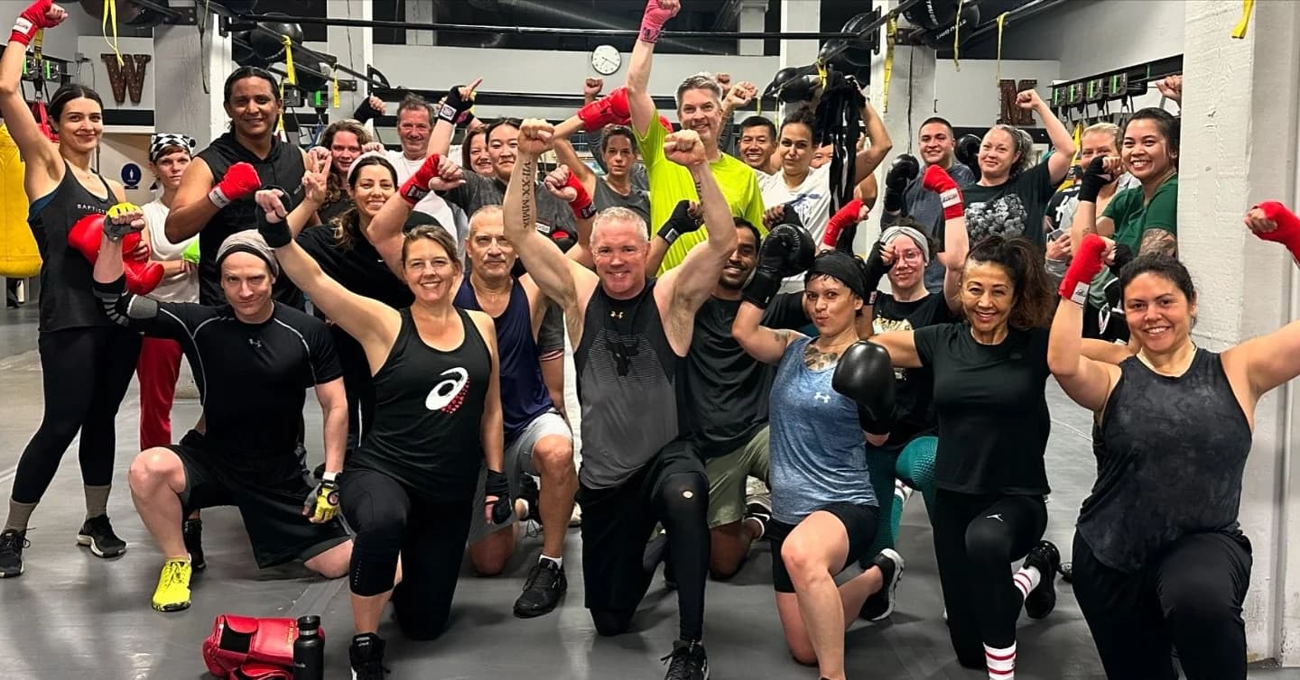 Large group class with arms and gloves raised on the HIIT floor